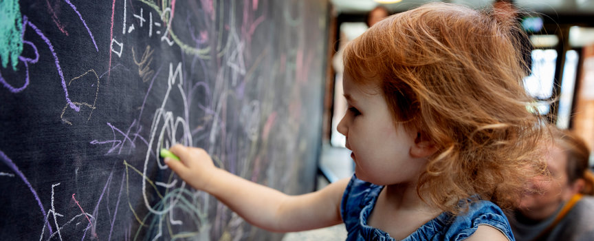 En liten tjej som målar på en tavla