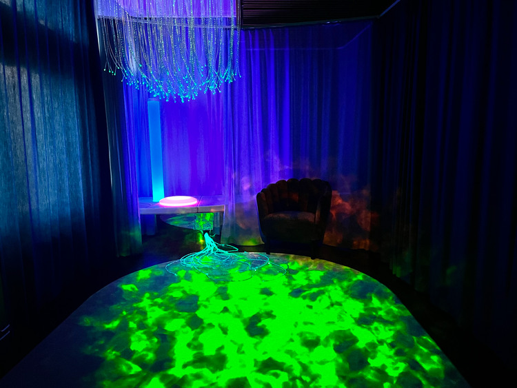 Bild på sinnesrummet med fin grön färg på mattan som ser ut som vatten och sagofåtöljen i bakgrunden