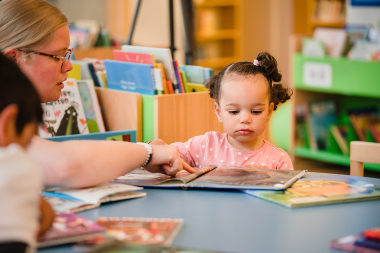 En vuxen som läser en bok för ett barn på biblioteket 