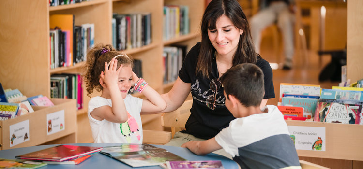 en mamma och två barn som leker och skrattar på biblioteket 