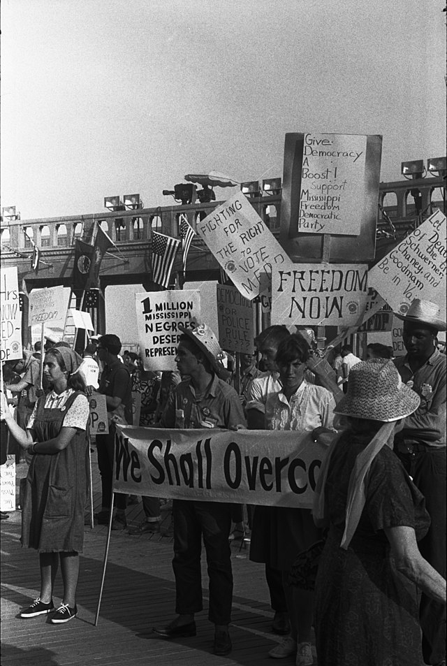 Demonstranter med plakat: we shall overcome