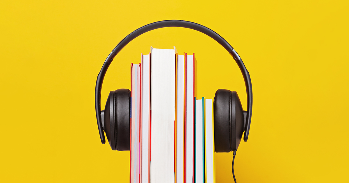 En hörlur som sitter över tryckta böcker med gul bakgrund 